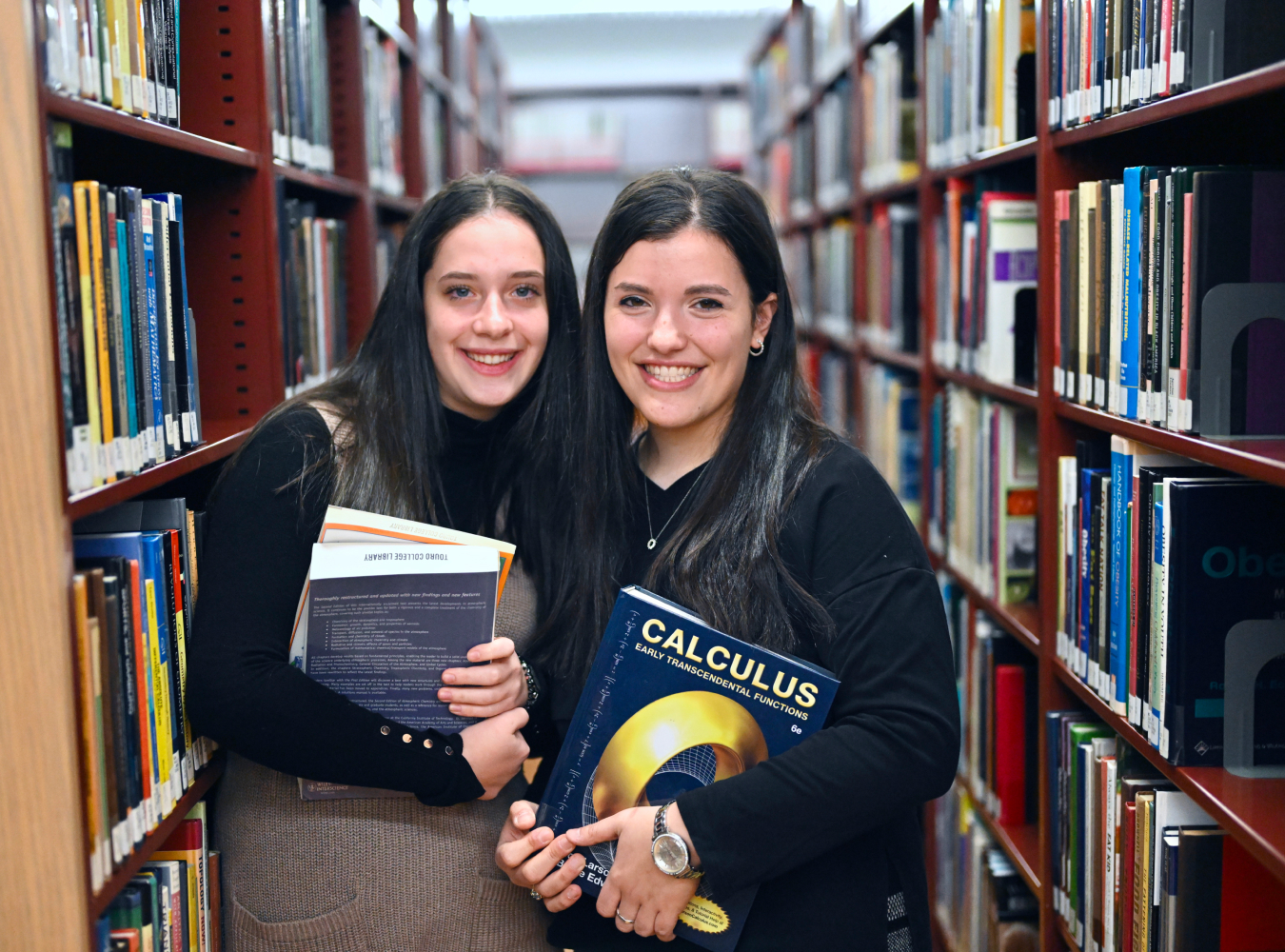 Two female LAS students holding books in library