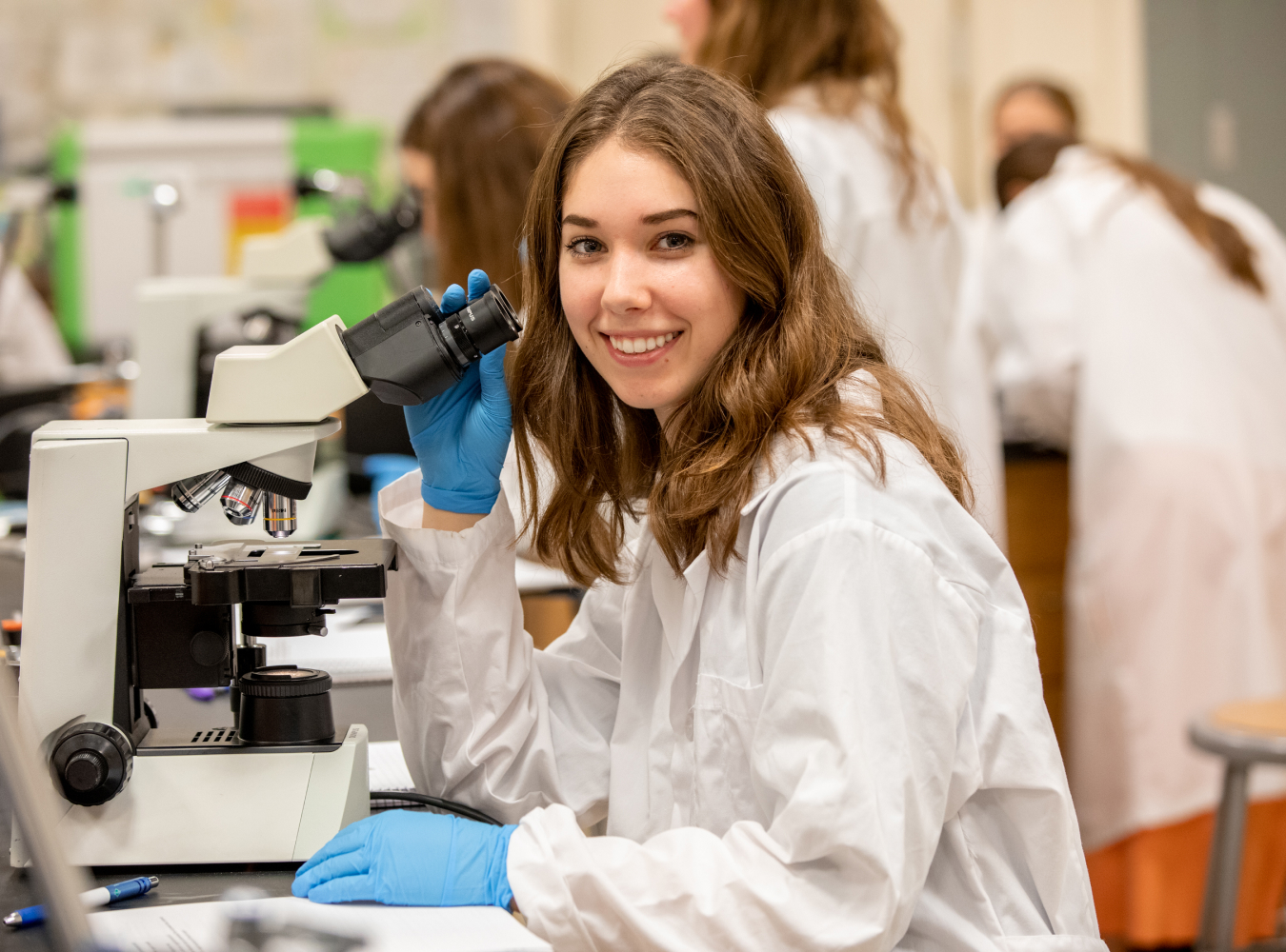 LCW student smiling with microscope in lab