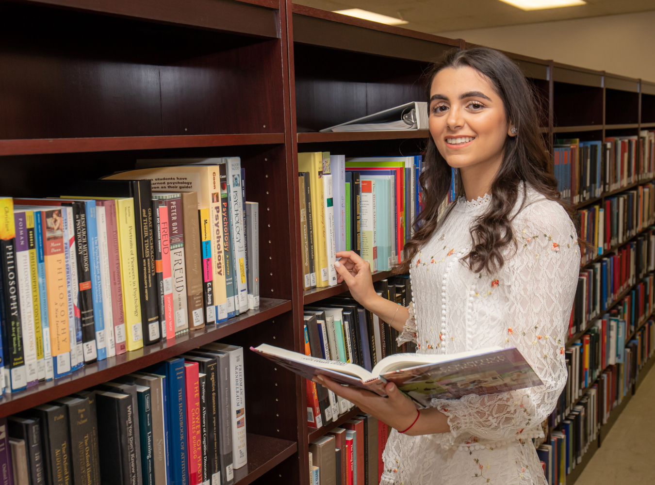 Female student holding book in library