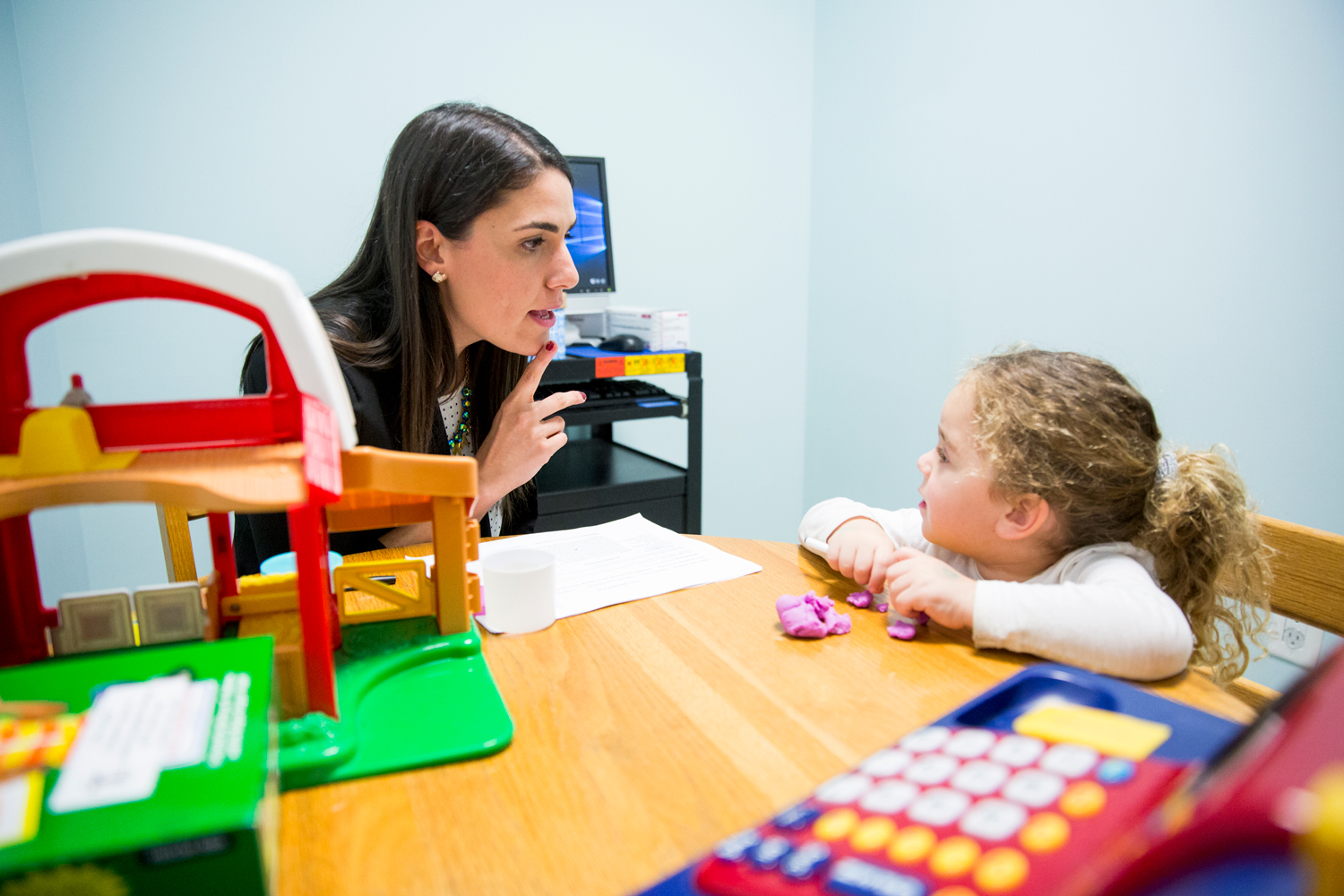 Speech-language pathologist working with young client at table