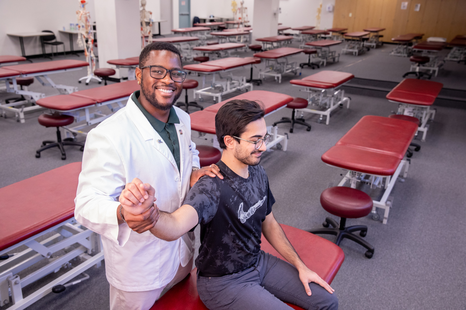 Ronald Lontchi smiling while wearing white coat and practicing techniques in classroom